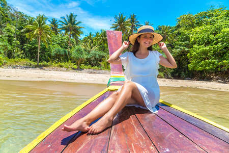 Happy traveler woman relaxing on boat near tropical island in Thailandの写真素材