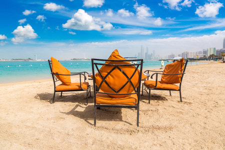 Sunbeds and umbrellas at the beach of luxury hotel in Abu Dhabi in a summer day, United Arab...