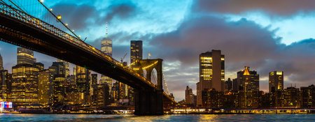 Panorama of  Brooklyn Bridge and panoramic night view of downtown Manhattan after sunset in New York City, USAの写真素材