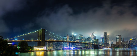 Panorama of  Brooklyn Bridge and panoramic night view of downtown Manhattan after sunset in New York City, USAの写真素材