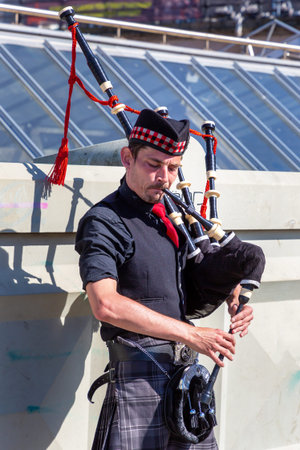 EDINBURGH, UK - JUNE 11, 2022: Bagpiper playing music with bagpipe near Edinburgh Castle in...