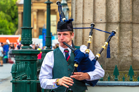EDINBURGH, UK - JUNE 11, 2022: Bagpiper playing music with bagpipe near Edinburgh Castle in...