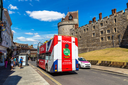 WINDSOR, UK - JUNE 19, 2022: Open-top Hop-on Hop-off Bus TOOTbus near Windsor Castle in Windsor in a sunny summer day, UKのeditorial素材