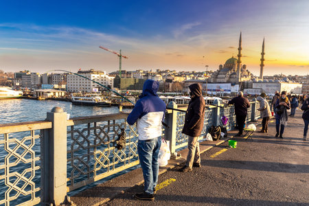 ISTANBUL, TURKEY - APRIL 10, 2022: Fishermen on Galata bridge in Istanbul, Turkey in a sunny dayのeditorial素材