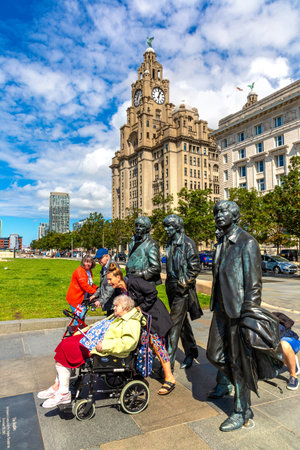 LIVERPOOL, UK - AUGUST 16, 2023: Tourists take pictures in front of The Beatles Statue in Liverpool stands at the Pier Head on the side of Ðºiver Mersey in a sunny day, United Kingdomのeditorial素材
