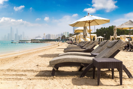 Sunbeds and umbrellas at the beach of luxury hotel in Abu Dhabi in a summer day, United Arab Emiratesの写真素材