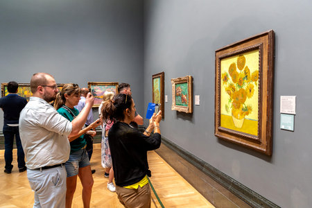LONDON, UK - SEPTEMBER 8, 2023: People looking at the oil paintings SUNFLOWERS by Vincent van Gogh...