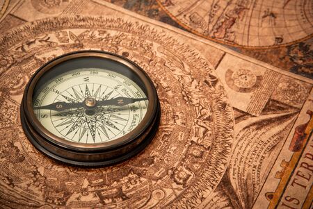 Antique compass lying on old style map. Sepia toned.の写真素材