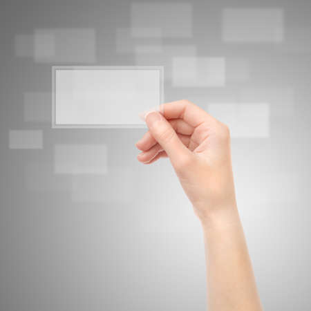 Female hand holding translucent electronic business card on a gray background. XXXL size, ultra quality.の写真素材