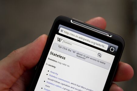 Kiev, Ukraine - May 20, 2011: Hand hold HTC Desire HD with Wikipedia search web page on screen.のeditorial素材