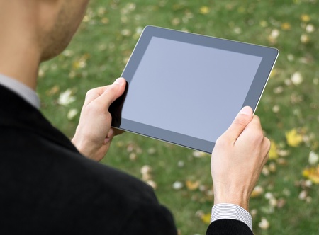 Businessman in a park holding a touch screen device.の写真素材