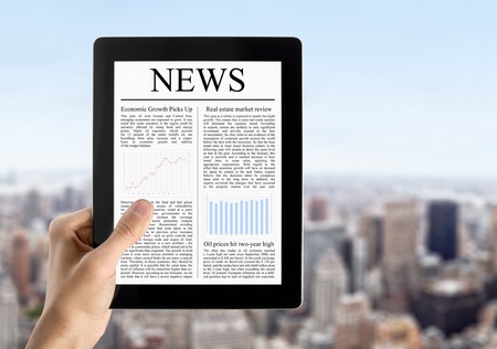 Man hands are holding touch screen device with news. Blurred cityscape with skyscrapers on background.の写真素材
