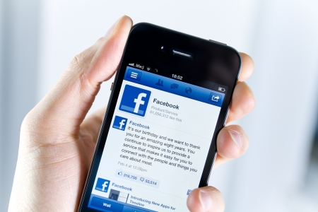 Kiev, Ukraine - February 08, 2012: A man holding Apple iPhone4 with a Facebook application on the screen. Apple iPhone4 developed by Apple inc. in June, 2010. Facebook celebrates the eighth anniversary on February 4.のeditorial素材