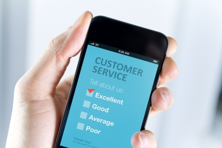 Men s hand holding modern mobile phone with customer service survey form on a screen  Red tick on excellent choice showing customer satisfaction の写真素材