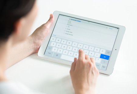 KIEV, UKRAINE - MAY 21, 2014: Woman holding a white Apple iPad Air and typing for search Google web page in Safari browser. The Google search most used web page in the world, owned by Google inc. のeditorial素材