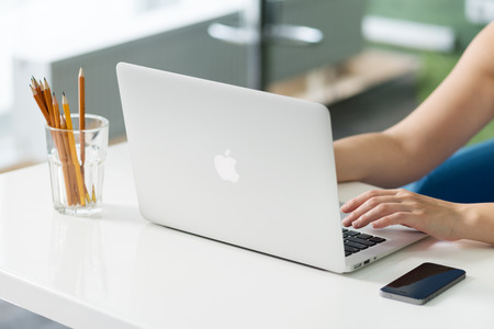 KIEV, UKRAINE - MAY 21, 2014: Woman sitting at the desk and typing text on a brand new Apple MacBook Air. The last version was released in April 29, 2014, designed and developed by Apple inc. のeditorial素材