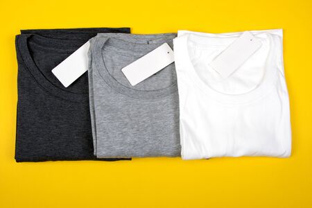 Dark Grey, Grey and White T-Shirts on Bright Yellow Background. New Apparel in Monochromatic Shadows.の写真素材