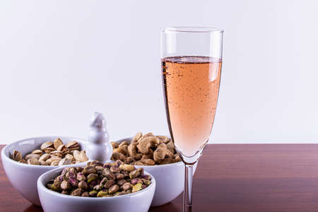 Glass of Pink Sparkling Wine with Nuts Mixed. .の写真素材