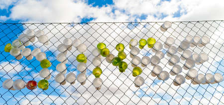 Green and white plastic cups on a fence spelling the spanish word forの写真素材