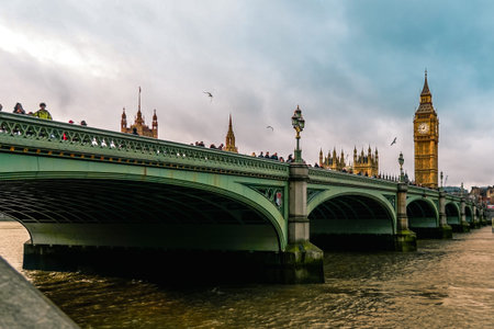 The Big Ben of London with unrecognizable tourists walking along the sidewalk. With the view of the...