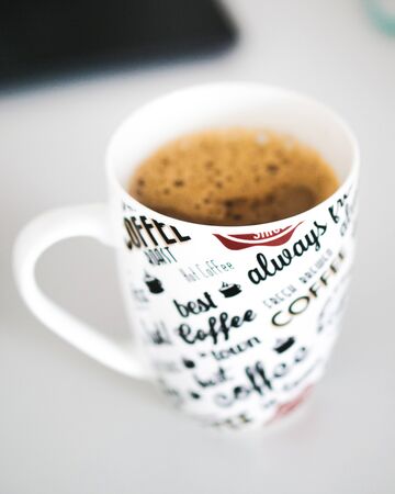 A cup of coffee with written letters on the cupの写真素材