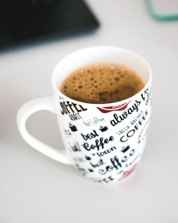 A cup of coffee with written letters on the cupの写真素材