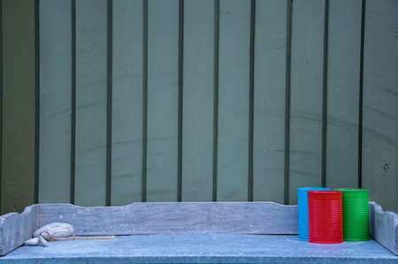 A rustic wooden table with three decorative painted cans against a plank wallの写真素材