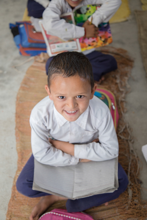 Smiling Indian/Asian Village School Boy Portrait, sitting in the floor of his classroomの写真素材