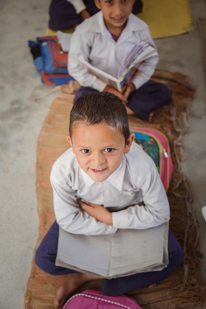 Smiling Indian/Asian Village School Boy Portrait, sitting in the floor of his classroomの写真素材