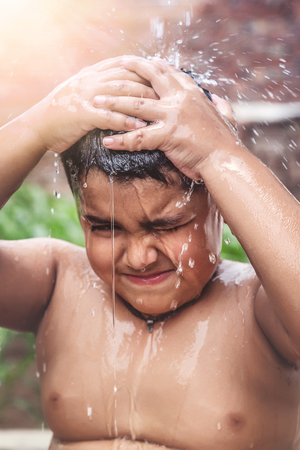 A child cooling down the heat with tap water during hot day in Indiaの写真素材