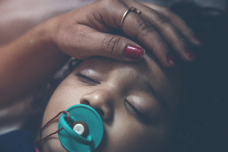 Baby asleep with pacifier while parents caressの写真素材