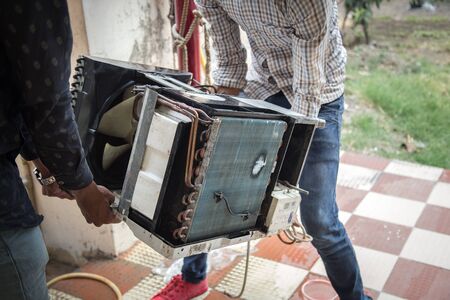 Worker cleaning window air conditioner by water for clean a dust on it in customer home when maintenance service. Breath, repair.の写真素材