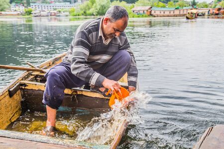 An old man removing water which has entered the broken boat.の写真素材
