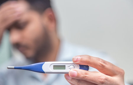 Novel corona virus COVID-19 -Sad man with tensed face holding digital thermometer, measuring body...