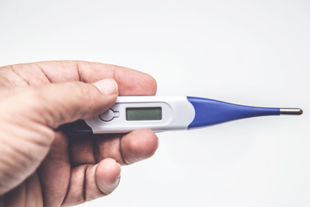 Novel coronavirus COVID-19 - hand holding thermometer on white back ground. High temperature,...