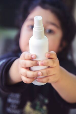 Close up of kid hand holding bottle with antiseptic cleaning gel. Kids use alcohol gel to wash hands to prevent coronavirus, Covid-19. World epidemic crisis.の写真素材