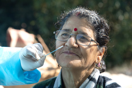 test in India, Medic wear PPE suits collects swab sample from the nose of a woman for   test via Rapid Antigen, to curb the spread of coroavirus.の写真素材