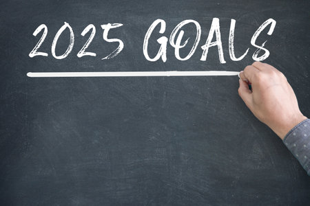 2025 Goals new year. A male hand writing new year goals on chalkboard.の写真素材