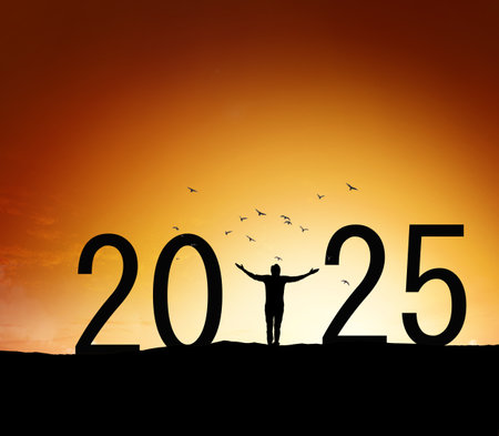 Young man standing Silhouette over mountain against orange sky to 2025 new year, New year conceptの写真素材