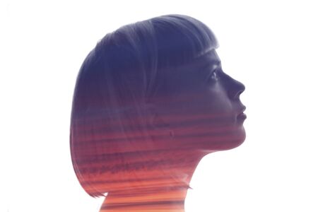 Young girl profile with double exposure purple sunset isolated on whiteの写真素材