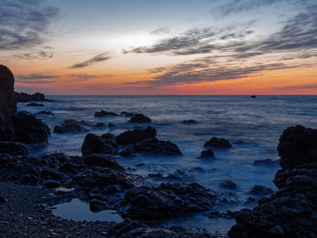 Landscape at dusk on the shore of a rocky beachの写真素材
