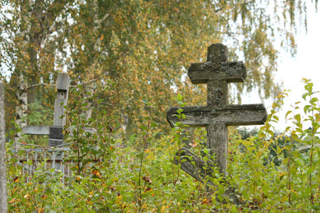 Abandoned cemetery and wooden cross in autumn