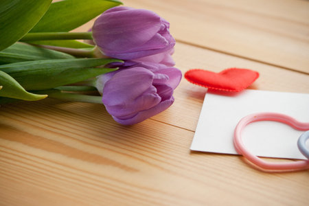 Beautiful tulip bouquet with hearts-symbols on wooden table