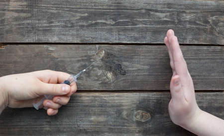 two hands and syringe on wooden background, drug addiction conceptの写真素材