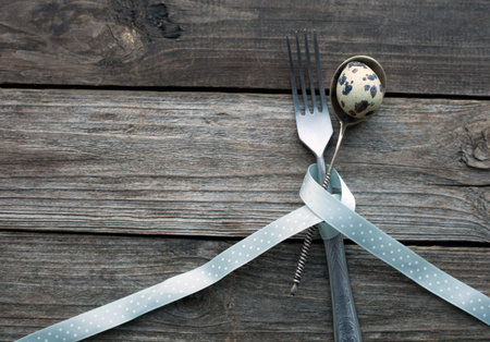 Quail egg in a spoon on a rustic wooden table