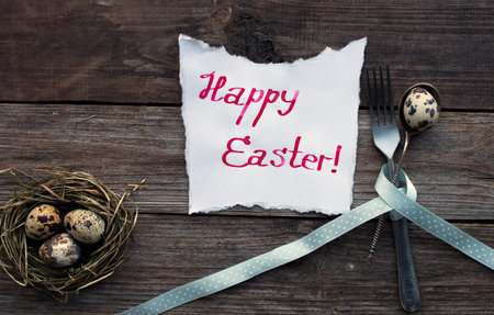 Quail eggs on a rustic wooden table and handwritten Happy Easter messageの写真素材