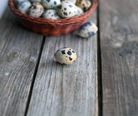 Quail eggs in a basket on a rustic wooden tableの写真素材