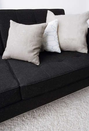  indoor setting, gray pillows laying on a black sofaの写真素材