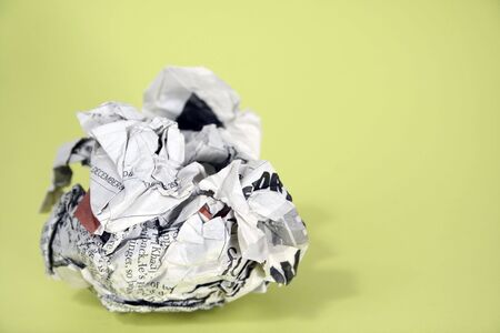 A crumpled up news paper page with lime green background.の写真素材