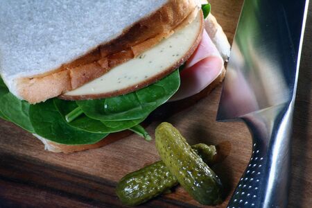 A sandwich and knife on wooden board.の写真素材